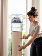 Frau schenkt sich Wasser am Wasserspender ein