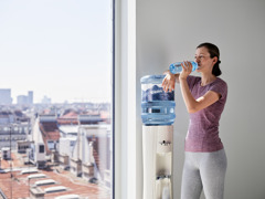 Sportliche Frau trinkt Wasser aus Wasserspender