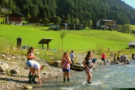 Kinder forschen am Fluss, in der Bildmitte das Haus des Wassers