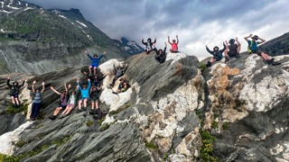 Die Nationalpark Junior Ranger sitzen nahe dem Pasterzengletscher auf einem riesigen Felsen