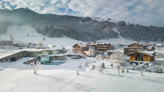 Luftaufnahme des Hotel Puradies im Winter, umgeben von verschneiten Wiesen.