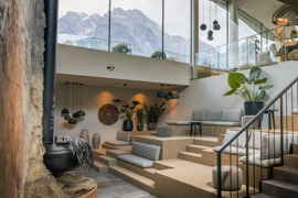 Kaminlounge des Heaven Spa mit gem&uuml;tlicher Atmosph&auml;re und Glasfront mit Sicht auf die Bergkulisse.