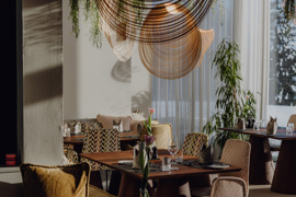 Gourmetrestaurant Essenz mit sch&ouml;n gedeckten Tischen und Glasfront mit Blick auf die Winterlandschaft.