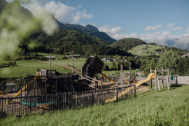 Abenteuerspielplatz im Sommer, umgeben von gr&uuml;nen Wiesen.