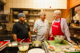 Auf den Bildern sieht man Gäste und Mitarbeiter:innen eines Restaurants. Die Menschen sind fröhlich und unterhalten sich, manche arbeiten - sie servieren Speisen oder kochen. Auf den Bildern sieht man Gäste und Mitarbeiter:innen eines Restaurants. Die Menschen sind fröhlich und unterhalten sich, manche arbeiten - sie servieren Speisen oder kochen.