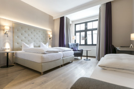 Helles Dreibettzimmer im Hotel Sailer mit Doppelbett, Einzelbett und gemütlichem Sitzbereich. Helles Dreibettzimmer im Hotel Sailer mit Doppelbett, Einzelbett und gemütlichem Sitzbereich.