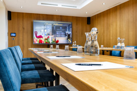Moderner Seminarraum im Hotel Sailer mit großem Bildschirm, langen Holztischen und blauen Stühlen. Moderner Seminarraum im Hotel Sailer mit großem Bildschirm, langen Holztischen und blauen Stühlen.