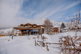 Haupteingang vom Naturresort Puradies im Winter mit Bergen im Hintergrund.