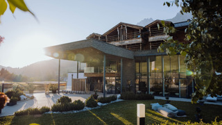 Haupteingang vom Naturresort Puradies im Sommer mit Bergen im Hintergrund.