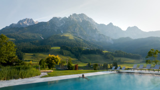 Person im Infinitypool vom Heaven Spa im Naturresort Puradies mit Blick auf die Berge im Sommer.
