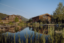 Naturbadeteich im Naturresort Puradies mit Hotelgeb&auml;ude Traumquartier und Saunahaus im Hintergrund.