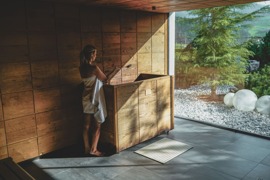 Person im Saunahaus vom Naturresort Puradies mit Blick in den Garten.