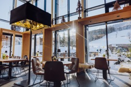 Sitzbereich in der Bar Freiraum im Naturresort Puradies mit Blick in die Winterlandschaft.