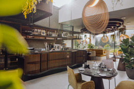 Gedeckte Tische im Gourmetrestaurant Ess:enz im Naturresort Puradies mit Frontcooking-Theke im Hintergrund.