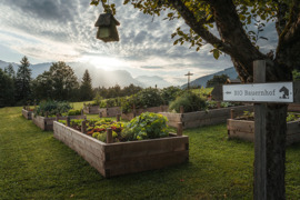 Gem&uuml;segarten mit Hochbeeten im Naturresort Puradies mit Bergen im Hintergrund.