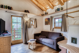 Wohnbereich mit Sofa und Kachelofen im Chalet vom Naturresort Puradies.