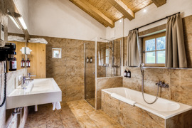 Badezimmer mit Badewanne und Dusche im Chalet vom Naturresort Puradies.