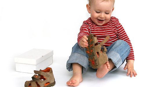 Kleinkind spielt mit Sandalen