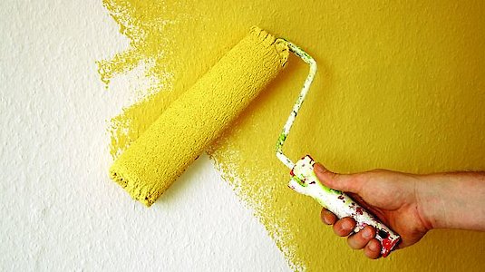Gelbe Malerrolle auf Wand