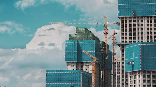 Skyscrapers under construction with construction cranes. Copyright by C Dustin on Unsplash.