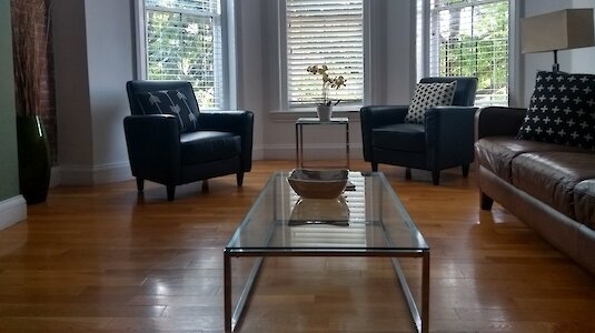 Modern living room with wooden floor, seating and a view of a tree. Copyright by Susanne Stark.