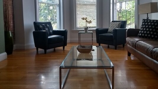 Modernes Wohnzimmer mit Holzboden, Sitzgelegenheiten und Ausblick auf einen Baum. Copyright by Susanne Stark.